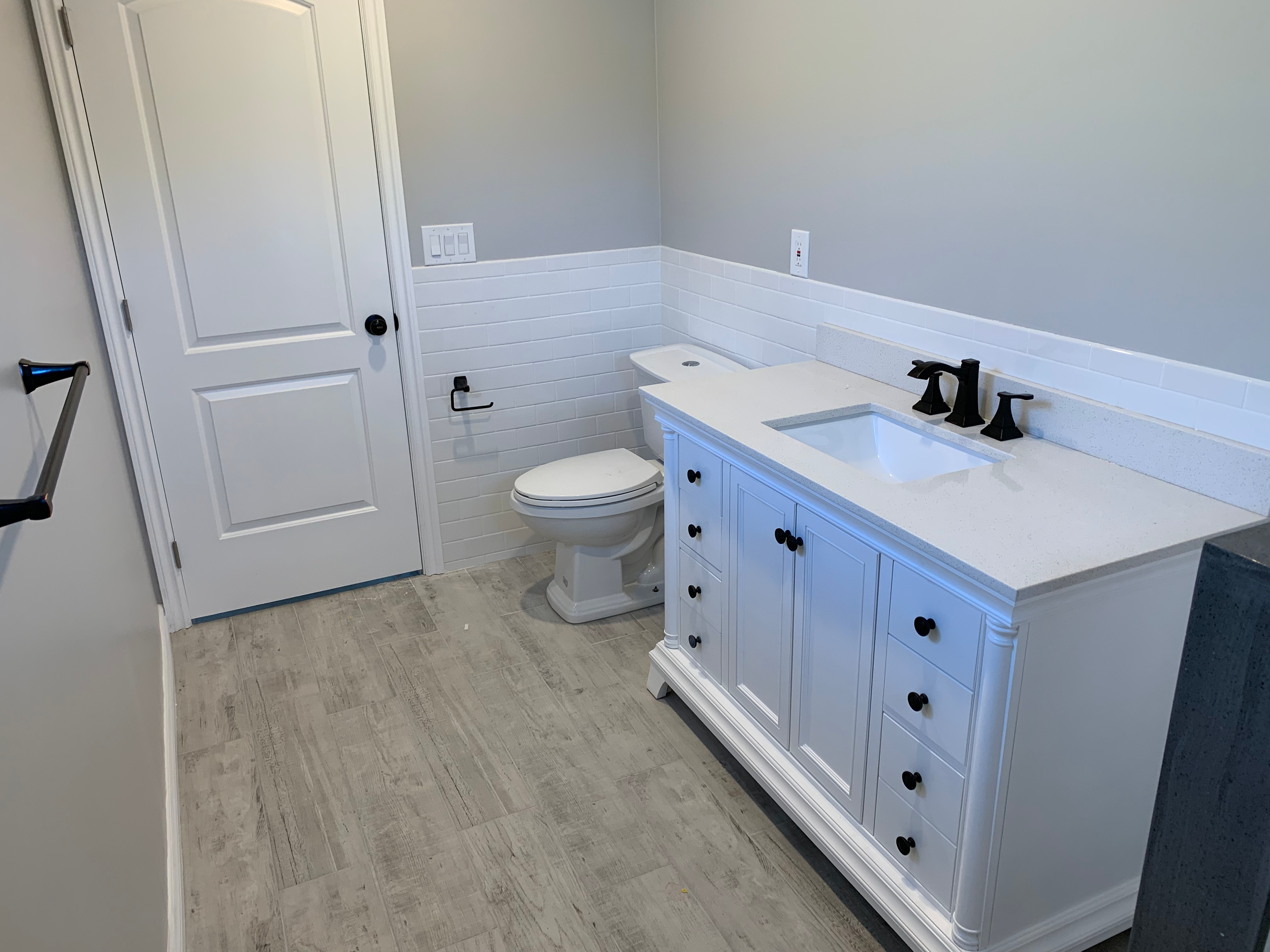 Renovated bathroom with white vanity, subway tile, and wood-look flooring